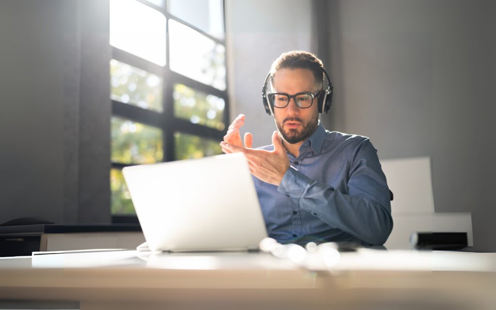 man speaking on a webinar in front of a computer