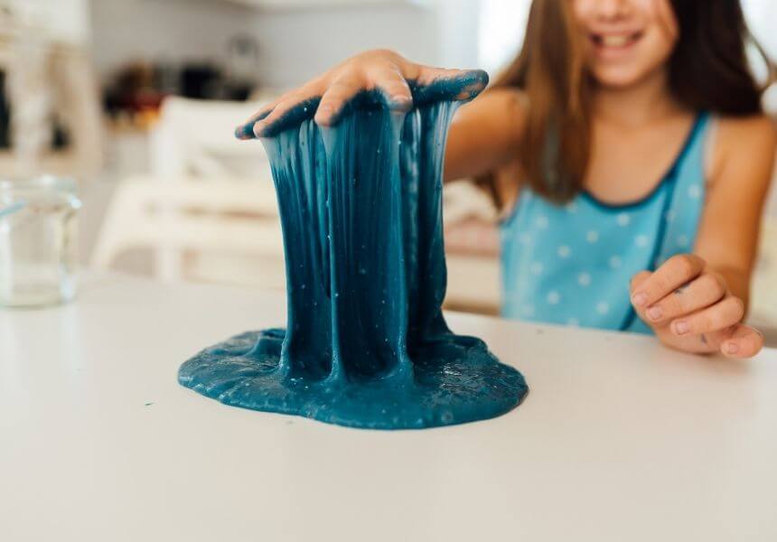 a child playing with a sticky substance that is stuck to their hand