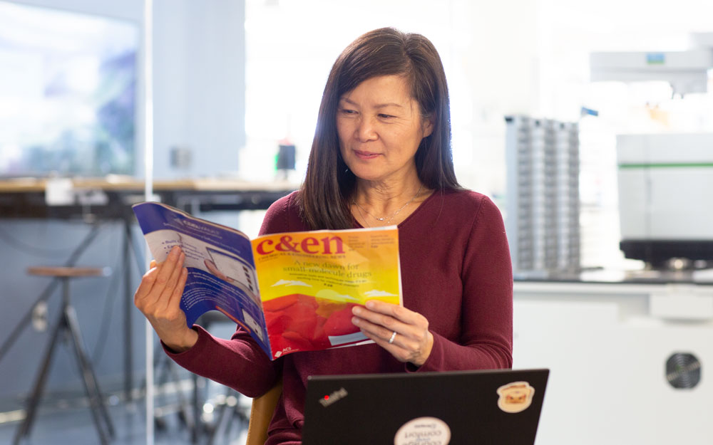 scientist reading a copy of C&EN in their lab