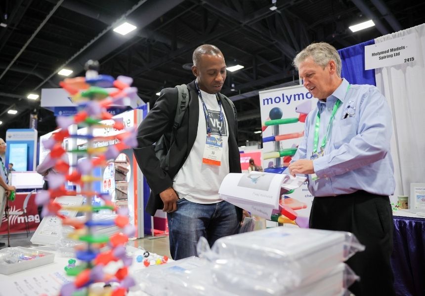 An exhibitor sharing information with a science conference attendee