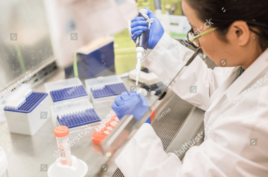 a scientist correctly using a pipette in the lab with only potential issue of safety glasses not being worn